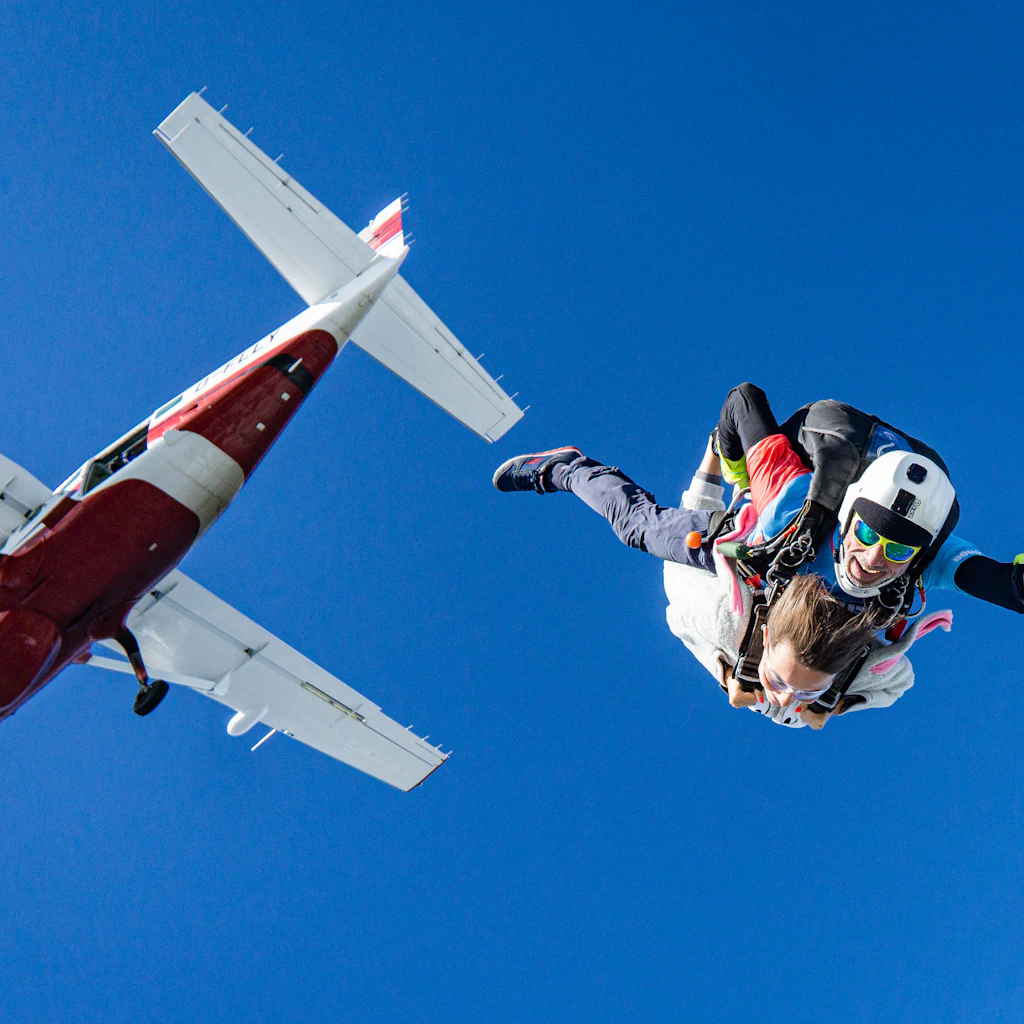 Parachutistes sautant d'un avion dans un ciel bleu
